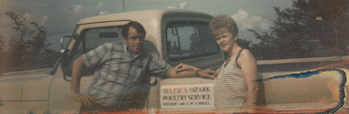 Two people standing in front of a Wades ozark poultry service truck