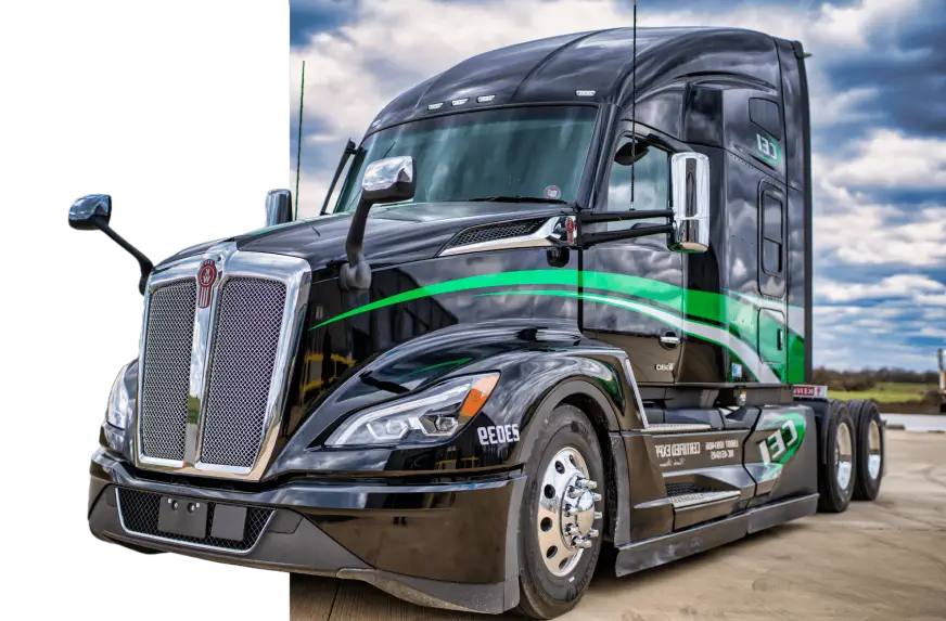Black semi-truck with green accents parked on concrete under a partly cloudy sky, photographed from a low front angle.